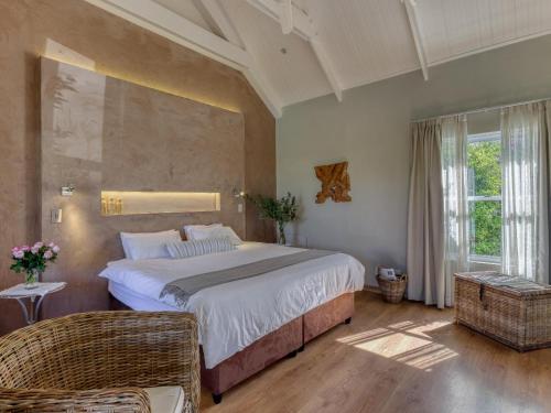 a bedroom with a large bed and a chair at Explorer Guesthouse in Somerset West