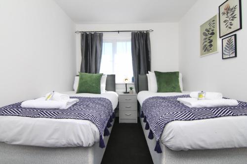 two twin beds in a room with a window at Tranquil 4Bed Retreat - 3 Min to M6, 10 Min to Coventry City Centre in Coventry
