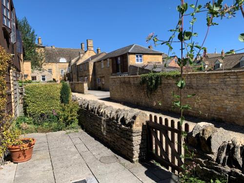 una pared de ladrillo y una valla en una ciudad en Centre Chipping Campden - 3 Bedroom Cottage for 5, en Chipping Campden