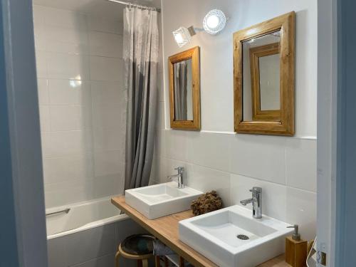 La salle de bains est pourvue de 2 lavabos, d'un miroir et d'une baignoire. dans l'établissement Maison dans sa Jungle, aux milliers d’espèces…, à Montmagny