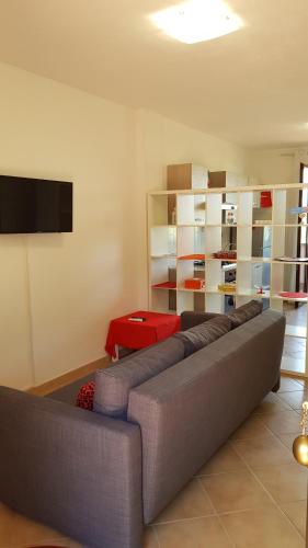 een woonkamer met een grijze bank en een televisie bij A CASA DEL SOLE in Palaia