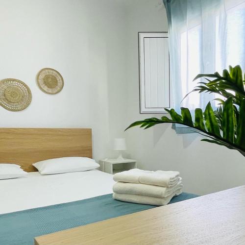 a white bedroom with a bed and a plant at Casa do Carmo in Sousel