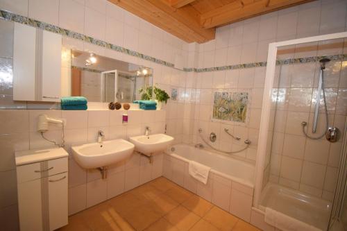 a bathroom with two sinks and a shower and a tub at Landhotel Steigerwaldhaus in Burghaslach