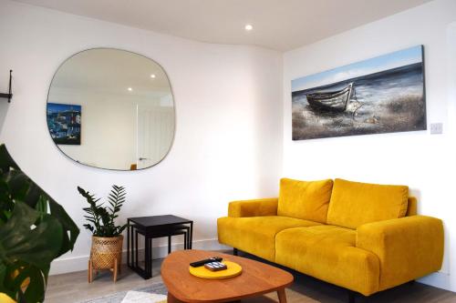 a living room with a yellow couch and a mirror at The Old Captains Lookout in Falmouth