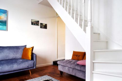 a living room with a couch and stairs at Cockleshell Cottage in Falmouth