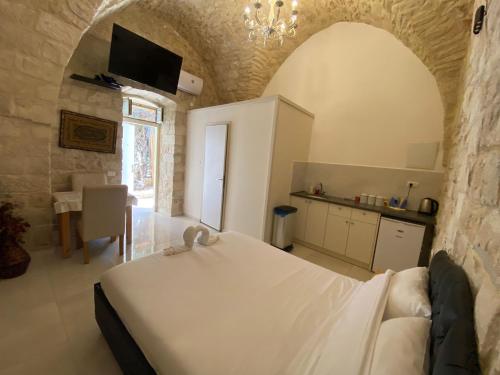 sypialnia z białym łóżkiem w kamiennej ścianie w obiekcie Mendy's Accommodation w mieście Safed