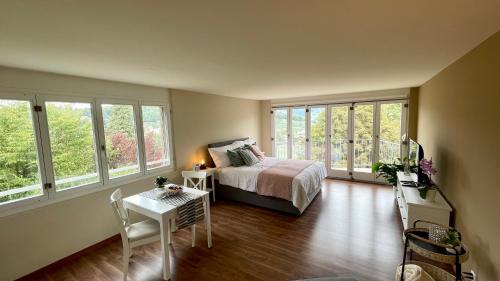 a bedroom with a bed and a table and windows at Hotel Movieworld in Spiez