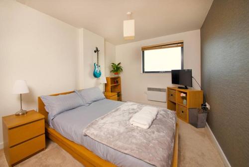 a bedroom with a bed and a television in it at Free parking- Central water-side apartment in Flixton