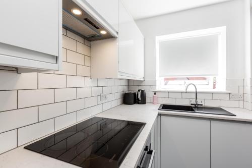 a white kitchen with white cabinets and a sink at Princes - 2 Bedrooms Parking Wi-Fi - Cozy Pads in Preston