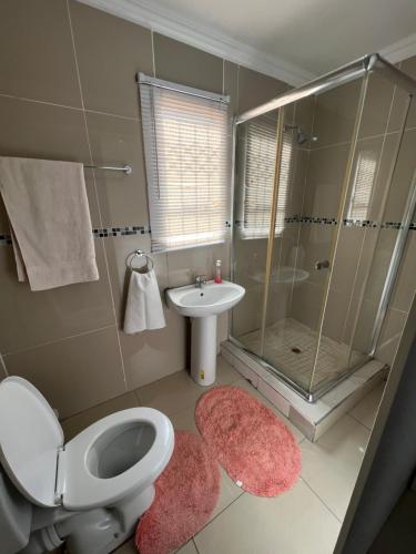 a bathroom with a toilet and a shower and a sink at Oteng Lifestyle BnB in Rustenburg