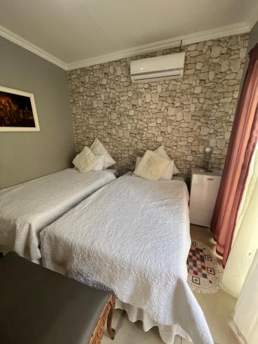 two beds in a bedroom with a stone wall at Oteng Lifestyle BnB in Rustenburg