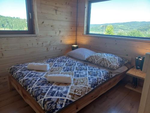 1 cama en una cabaña de madera con 2 almohadas en Przystanek Jawory, en Wołkowyja
