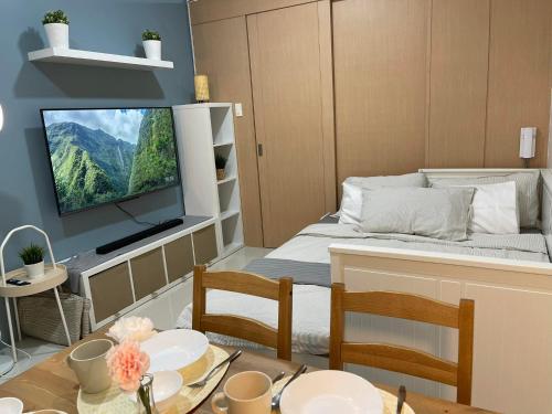 a small room with a bed and a table with chairs at 1 BR Cozy Modern-Style Condo with Balcony & 5-star amenities at Wind Residences in Tagaytay
