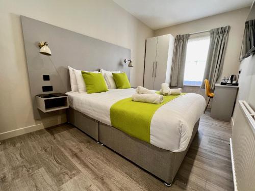 una camera da letto con un grande letto con cuscini verdi e bianchi di Pearl & Pebbles Eastbourne a Eastbourne