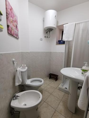 La salle de bains blanche est pourvue de toilettes et d'un lavabo. dans l'établissement Esclusivo Cortile Duca D'Aosta ai piedi dell'ETNA, à Viagrande