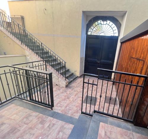 un conjunto de escaleras que conducen a una puerta negra en Esclusivo Cortile Duca D'Aosta ai piedi dell'ETNA, en Viagrande