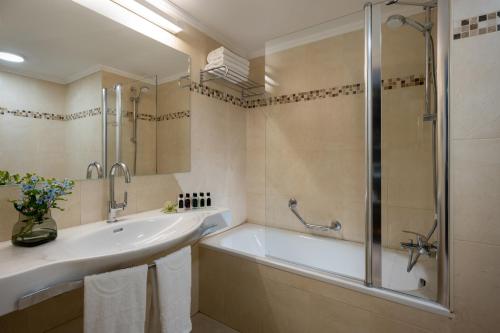 y baño con bañera, lavamanos y ducha. en Kfar Maccabiah Business & Sport Hotel, en Ramat Gan