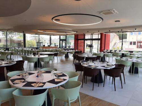 une salle à manger avec tables, chaises et fenêtres dans l'établissement Stella Maris, à Stella-Plage