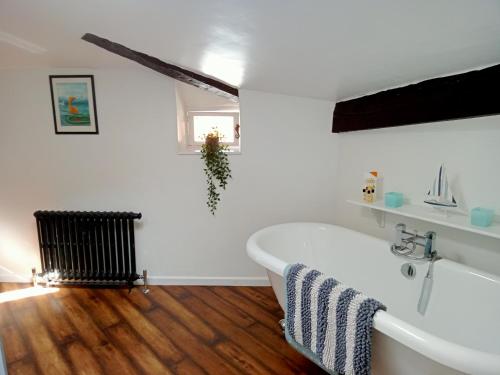 a bathroom with a white tub and a wooden floor at The Two Vines 2 bed house in Chez Ravard in Le-Vieux-Cérier