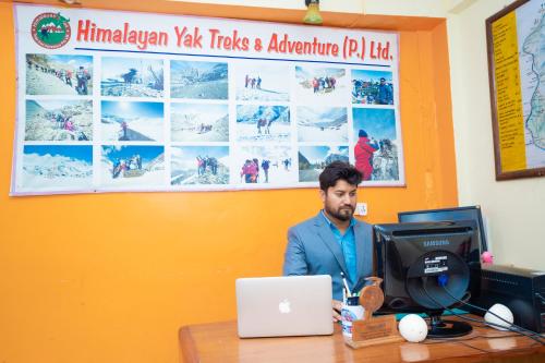 a man sitting at a desk with a laptop computer at Butterfly Lodge in Pokhara