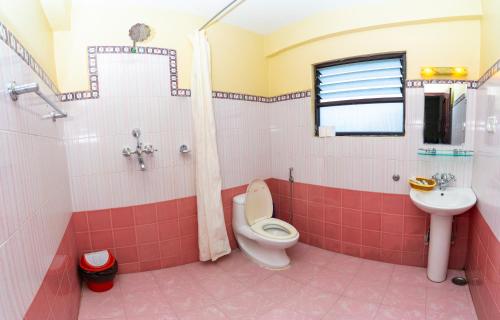 a pink bathroom with a toilet and a sink at Butterfly Lodge in Pokhara
