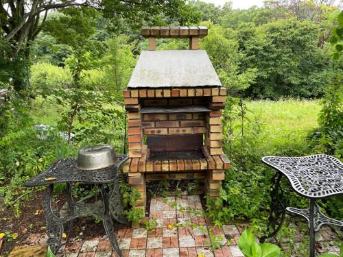 an outdoor brick oven with a table and a chair at HOKUTO SATOYAMA BASE in Hokuto