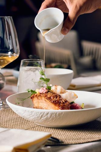 a person pouring a cup of coffee over a plate of food at La Fleur Boutique Hotel in Tivat