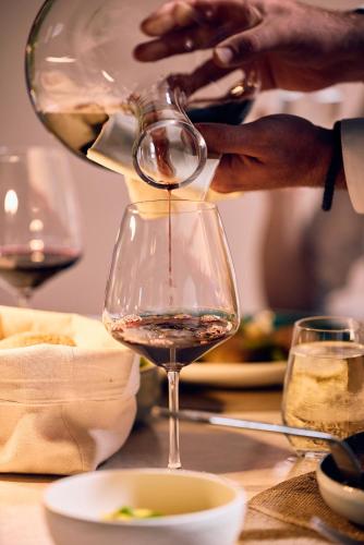 a person pouring wine into a glass on a table at La Fleur Boutique Hotel in Tivat