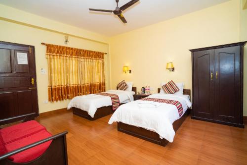 a bedroom with two beds and a window at Butterfly Lodge in Pokhara