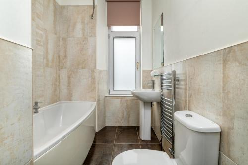 a bathroom with a tub and a sink and a toilet at Spacious 5-Bedroom Townhouse in the West-End in Aberdeen