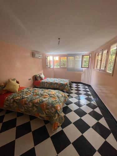 a bedroom with two beds and a checkered floor at Mehdia Ville in Plage de Mehdia