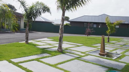 a stone walkway with palm trees in a yard at Coronation Court Motel in New Plymouth