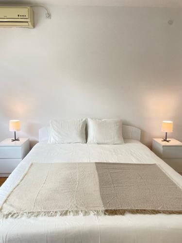 une chambre avec un grand lit blanc avec deux lampes dans l'établissement The Blue Velvet Apartment, à Belgrade