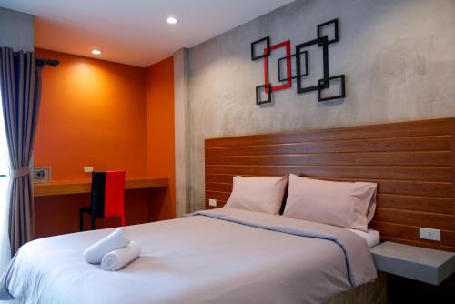 Schlafzimmer mit einem großen weißen Bett mit einem Kopfteil aus Holz in der Unterkunft B3 Hotel in Nakhon Si Thammarat