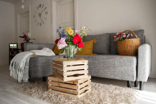 una sala de estar con un sofá gris con flores sobre una mesa en Apartamentai Šilutėje en Šilutė