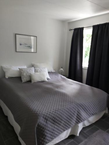 een slaapkamer met een groot bed en zwarte gordijnen bij Huset i skogen in Moss