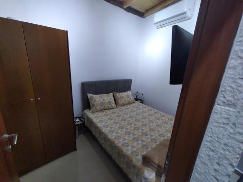 a small bedroom with a bed and a flat screen tv at Country-bumpkin's house in Karyótikon