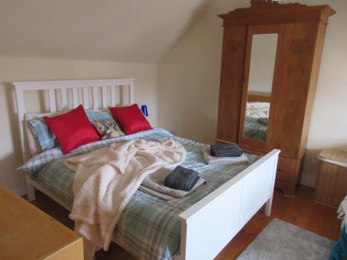 a bedroom with a bed with red pillows and a mirror at Anchor House in Pittenweem