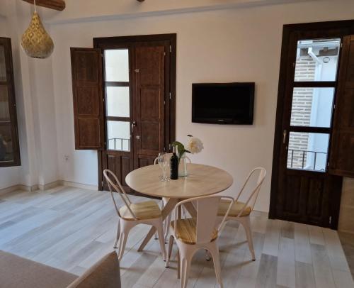 uma sala de jantar com mesa e cadeiras e uma televisão em Apartamentos Garam em Granada