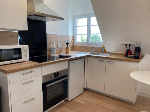 a kitchen with white cabinets and a microwave at La Brise Marine, calme, Océan, 350m plage in Loctudy