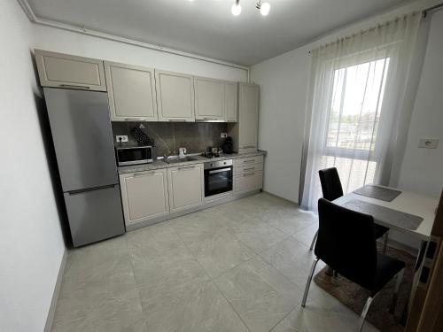 een keuken met witte kasten, een tafel en een koelkast bij Apartament Modern cu o Camera in Timişoara