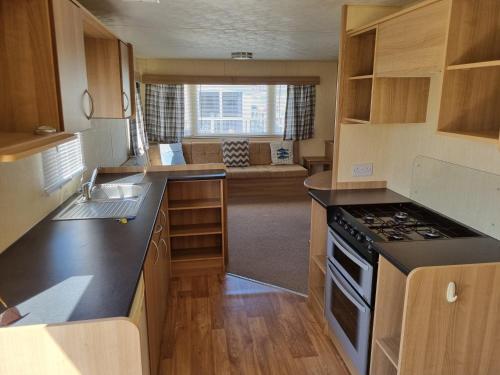 a kitchen with a sink and a stove top oven at PG49 8 BERTH PET FRIENDLY CARAVAN GOLDEN PALM in Chapel Saint Leonards