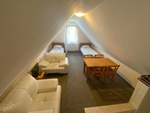 a attic room with white furniture and a table at HAMR Apartmány in Nové Hamry