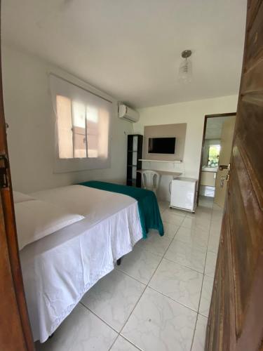 1 dormitorio con 1 cama blanca y TV en Pousada das Redes, en João Pessoa