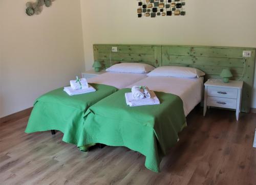 2 camas en una habitación con sábanas verdes y toallas en SOCIETA' AGRICOLA LAMBURE SRL en Popiglio