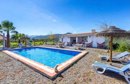 a swimming pool with two chairs and a house at Villas Cozyinns in Cártama