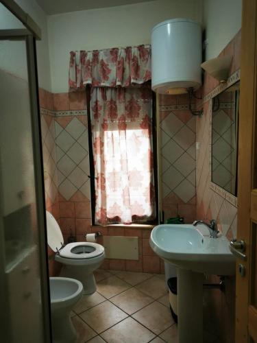 een badkamer met een wastafel, een toilet en een raam bij Casa Mastio in Galtellì
