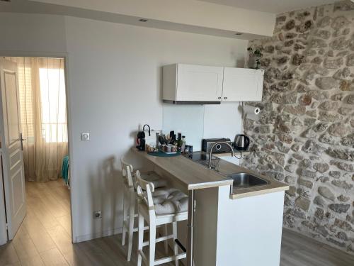 une cuisine avec un évier et un mur en pierre dans l'établissement Appartement La Tourraque côté mer, à Antibes
