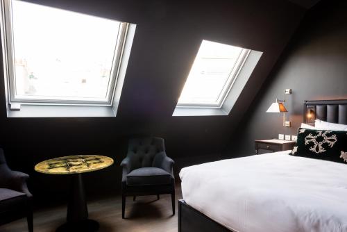 a bedroom with a bed and a table and two chairs at Hotel de Montesquieu in Paris