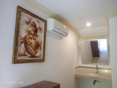 a painting on the wall of a bathroom with a sink at Karma House in Ubud